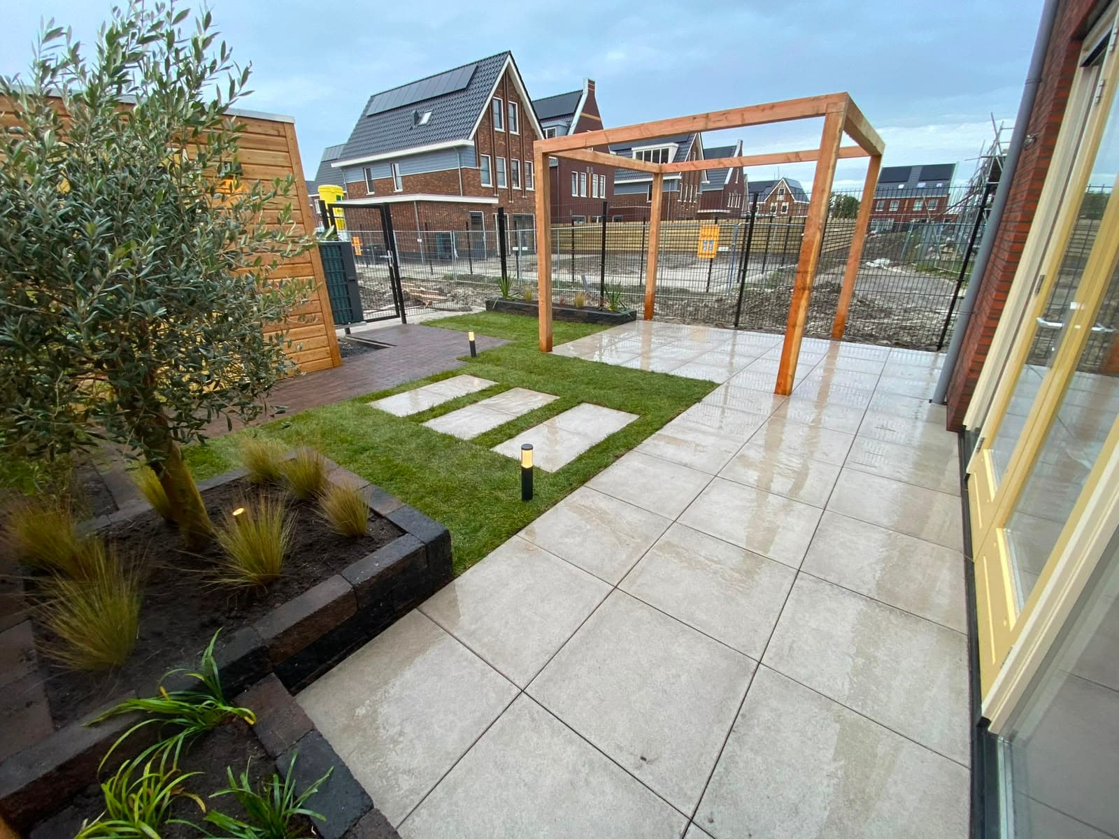 Houten pergola-frame boven een nieuw aangelegd terras met kunstgras
