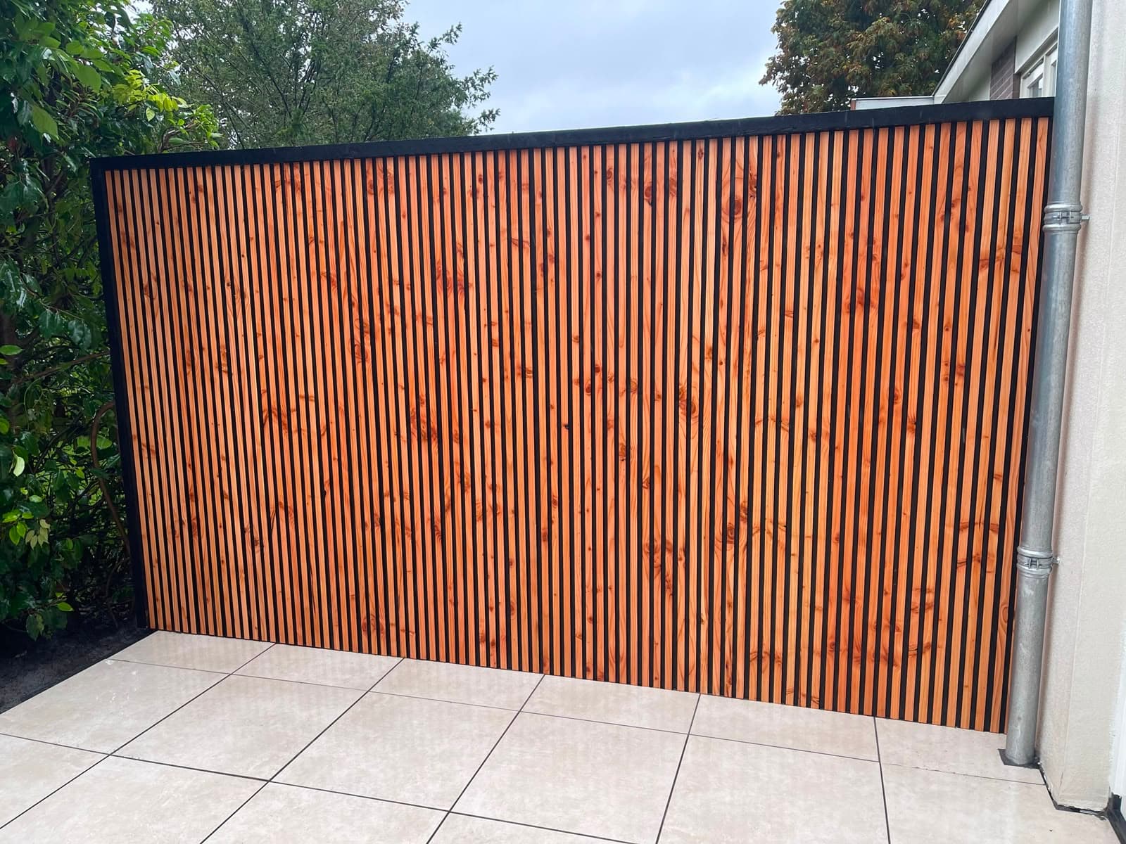 Verticale houten lamellenschutting op een tegelterras