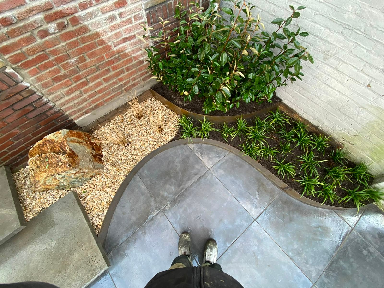 Hoek van een tuin met natuursteen, grind en vaste beplanting