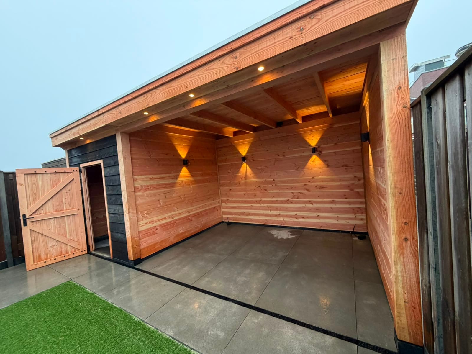 Houten berging met ingebouwde spotverlichting in de overkapping
